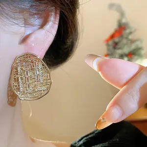Close-up detail of gold plated oval hollow stud earrings with sparkling zircons