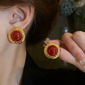 Dettaglio di orecchini vintage oro con cabochon rosso e bordo martellato a mano strutturato.