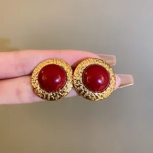 Dettaglio di orecchini vintage in oro stile francese con pietra rotonda rossa