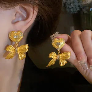Dettaglio di orecchini vintage dorati a fiocco con cuori di strass scintillanti