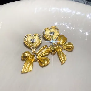 Dettaglio orecchini retrò francesi oro a cuore e fiocco con pavé di cristalli