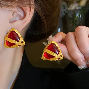 Dettaglio di orecchini geometrici vintage con pietra rossa e montatura in oro ritorto