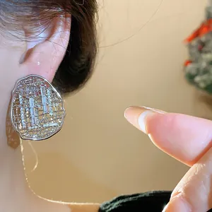 Close-up macro view of gold plated zircon oval hollow lattice stud earrings on ear