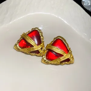 Dettaglio di orecchini vintage geometrici rossi triangolari con finitura dorata