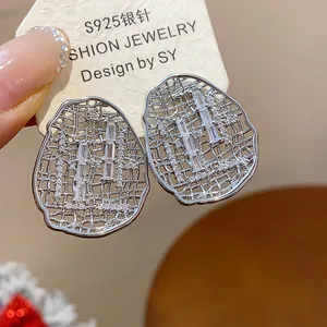 Macro detail of silver hollow oval stud earrings with clear zircon crystal inlays.