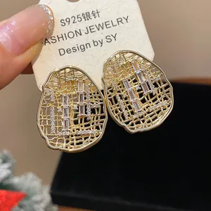 Macro detail of gold-plated hollow oval earrings with sparkling cubic zirconia stones