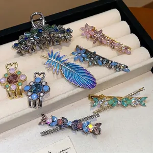 Elegant rhinestone flower and feather hair clip set displayed in a jewelry tray