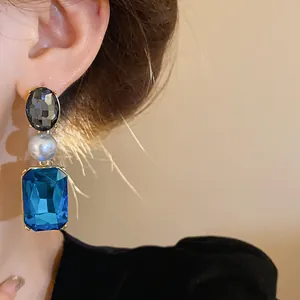 Elegant close-up of vintage court style dangling earrings with blue crystal and pearl detail