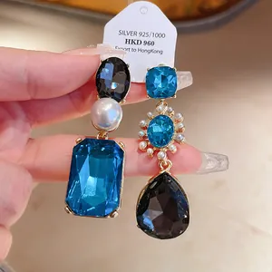 Detailed view of luxury vintage earrings featuring blue and black crystals with a pearl accent