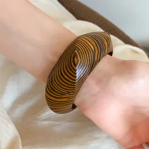 Close-up of vintage chunky wooden bangle with wood grain pattern on woman's wrist
