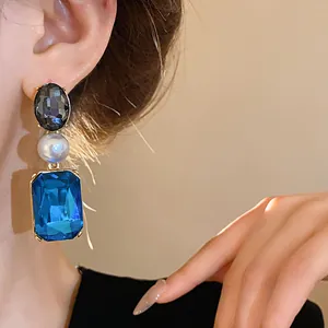 Detail showing vintage blue crystal and pearl drop earring worn on a stylish person's ear