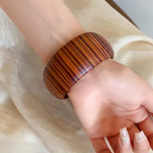 Close-up detail of retro wide wooden-patterned bangle shown on a female model wrist