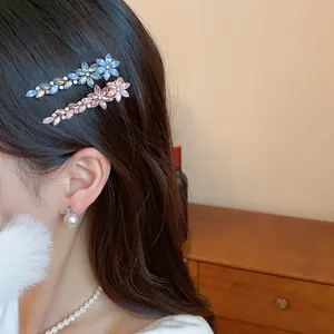 Detail of crystal resin flower feather hair clips on model's dark hair