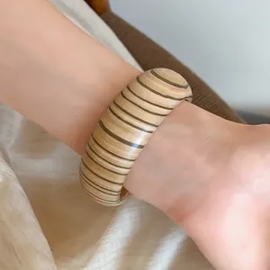 Detailed view of a vintage wooden bangle with fine horizontal stripes on a wrist.