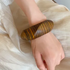 Close-up of a vintage oversized bangle featuring a bold yellow and black striped pattern.