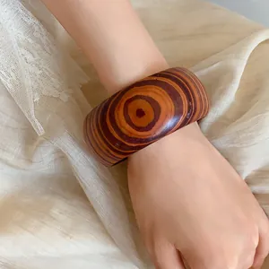 Close-up of a wide retro bangle featuring a unique concentric circle wood-grain pattern.