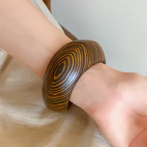 Macro detail of a vintage wide bangle featuring a bold circular wood grain pattern