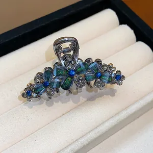 Close-up of elegant hair claw clip with sparkling rhinestones and green resin flowers