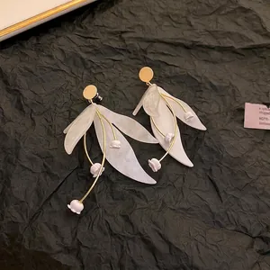 Elegant white flower and leaf statement earrings with gold wire detail on black background