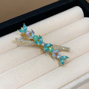 Close-up of teal resin flower and rhinestone detail on a gold-tone hair clip