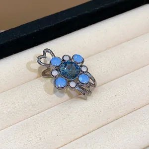 Close-up of blue flower rhinestone hair clip with heart-shaped metal detail in jewelry box.