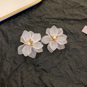 Detail macro view of white frosted petal flower earrings with pearl and gold center