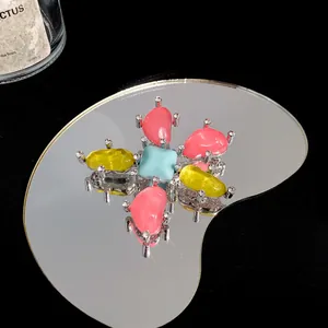 Detail-Makroaufnahme einer bunten Edelsteinbrosche mit Zirkonia auf einer Spiegelfläche
