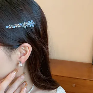 Detailed view of an elegant blue resin flower hair clip with sparkling rhinestones on hair