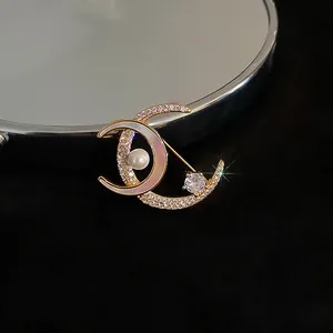 Detail einer vergoldeten Mondsichel-Brosche mit funkelnden Zirkonia und Perle
