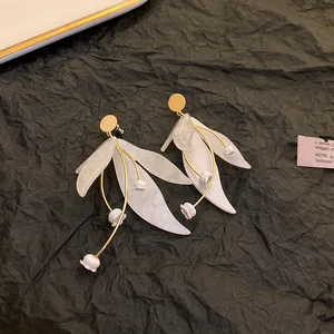 Macro detail view of elegant white leaf and lily of the valley flower statement drop earrings