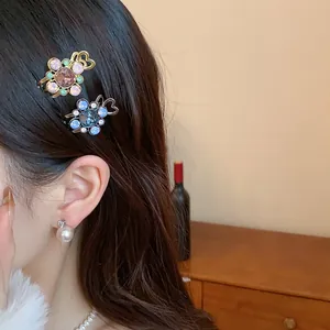 Detailed view of elegant floral rhinestone hair clips and pearl earring worn on hair
