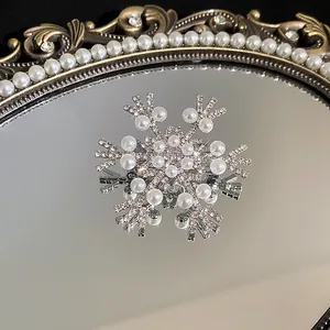 Nahaufnahme einer eleganten Schneeflocken-Brosche mit schimmerndem Zirkonia und Perlen.