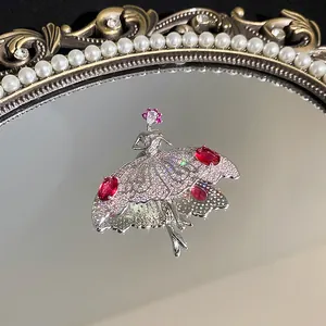 Detailaufnahme einer funkelnden Ballerina-Brosche mit roten Edelsteinen auf Spiegel
