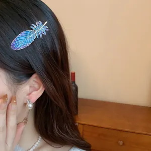 Close-up of a blue and purple gradient resin feather hair clip worn by a model in a warm setting