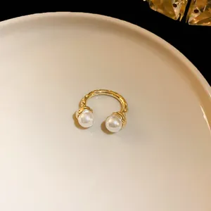 Close-up detail of a vintage style wrinkled gold open ring featuring elegant dual white pearls