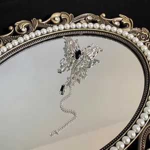 Detailansicht einer silbernen Schmetterlingsbrosche mit schwarzem Zirkon und Kettenquaste