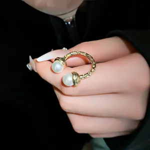 Close-up view of a gold-finish open ring featuring two elegant white pearls and texture.