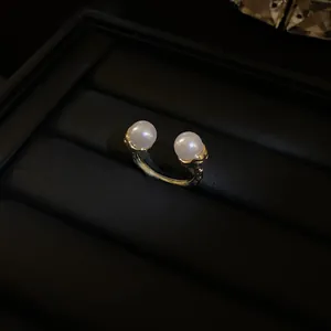 Detailed macro view of vintage gold pleated open ring adorned with two elegant white pearls