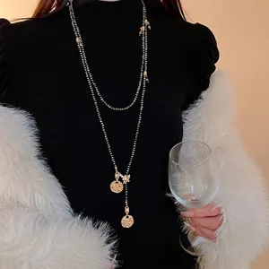 Elegant vintage bee and gold coin long sweater necklace worn over a black turtleneck