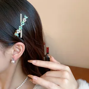 Elegant cyan crystal leaf hair clip worn on dark hair detail view