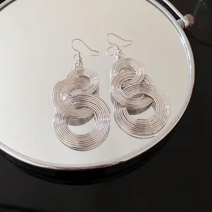 Detailansicht von silbernen runden Hohl-Quastenohrringen auf einer Spiegelfläche.
