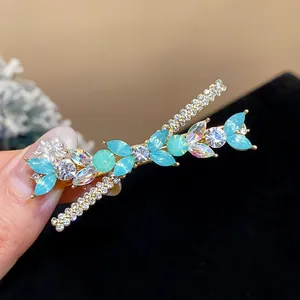 Close-up of elegant rhinestone and blue resin flower hair clip on a black background
