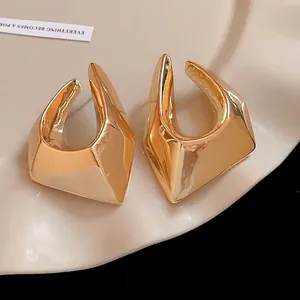 Chunky gold irregular geometric stud earrings in a minimalist and exaggerated style