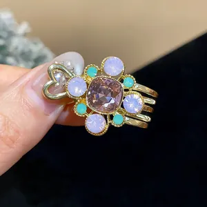 Close-up of a gold duckbill hair clip with colorful resin crystals and heart detail