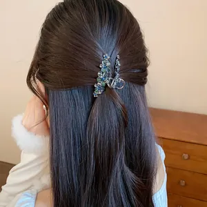 Detail shot of an elegant rhinestone flower feather hair clip styled in long dark wavy hair