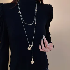 Detail view of a vintage long beaded necklace with gold bee and coin charms