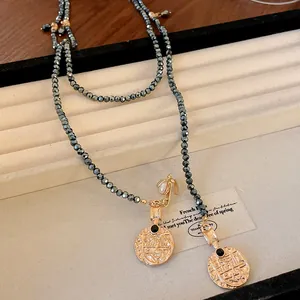 Detailed view of vintage gold coin pendants with bee motif on grey faceted bead necklace