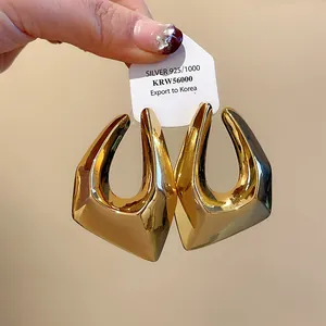 Macro view of chunky irregular geometric gold hoop earrings with silver needles