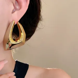 Detailed view of gold irregular geometric earring worn on a model for modern style.