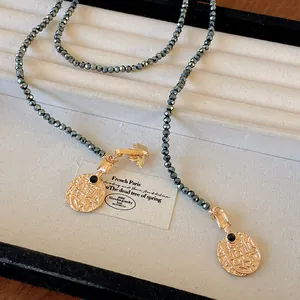 Detailed view of a vintage style long necklace featuring bee and gold coin charms on grey beads